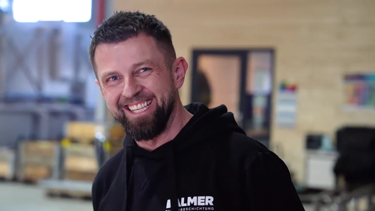 Valentin Dalmer lächelt im persönlichen Gespräch während der Unternehmensreportage in seiner Produktionshalle