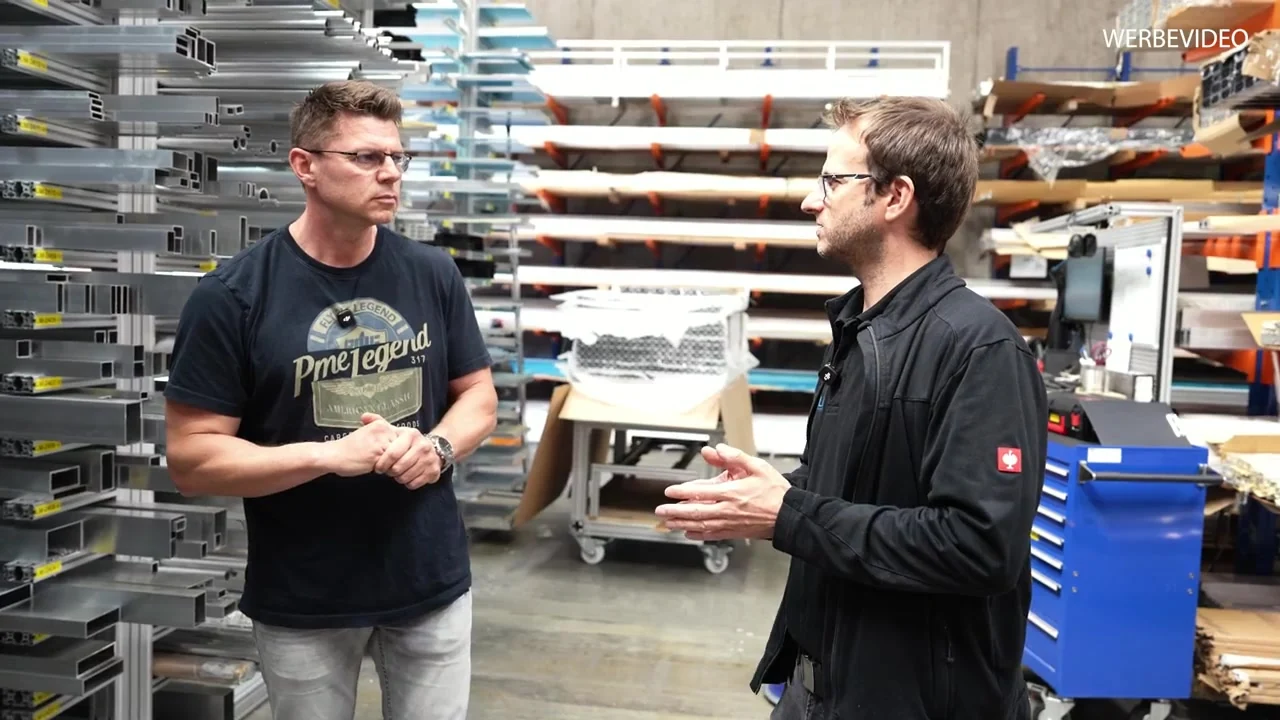 Igor Welder im Gespräch bei DOLD Mechatronik zwischen Aluminiumprofilen und Werkstattausrüstung