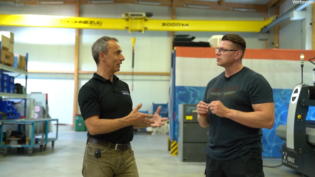 Igor Welder im Gespräch mit einem Ansprechpartner von MAXIMATOR JET neben einer OMAX-Wasserstrahlanlage
