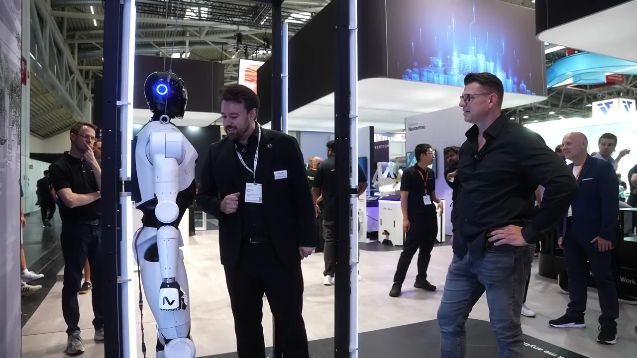 Igor Welder im Gespräch mit einem NEURA-Mitarbeiter neben einem humanoiden Roboter auf der automatica in München