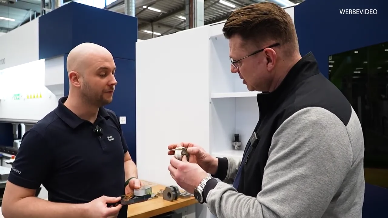 Igor Welder und ein TRUMPF-Mitarbeiter betrachten ein geschnittenes Musterteil direkt an der TruLaser-Anlage